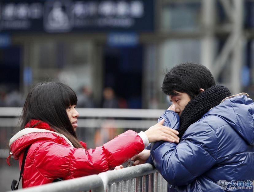 2012年1月8日，上海，火车站吻别的情侣。上海铁路局春运首日发送旅客超过80万人，在铁路上海站南广场验票大棚通往安检口区域的东西两侧，已经用半人多高的金属护栏围了起来，这里成为恋人“吻别”选择地，在寒冷的冬日里，形成了一道独特的风景线。（王炬亮/摄）